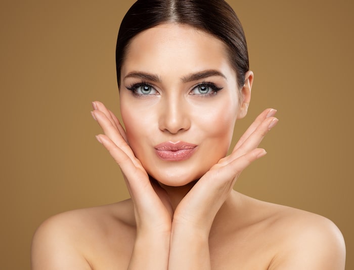 Beauty Model showing Cheekbones and Full Lips. Beautiful Woman Face Skin Care. Women Dermal Filler and Permanent Make up Cosmetology. Lip Augmentation Facial Lifting Spa Massage